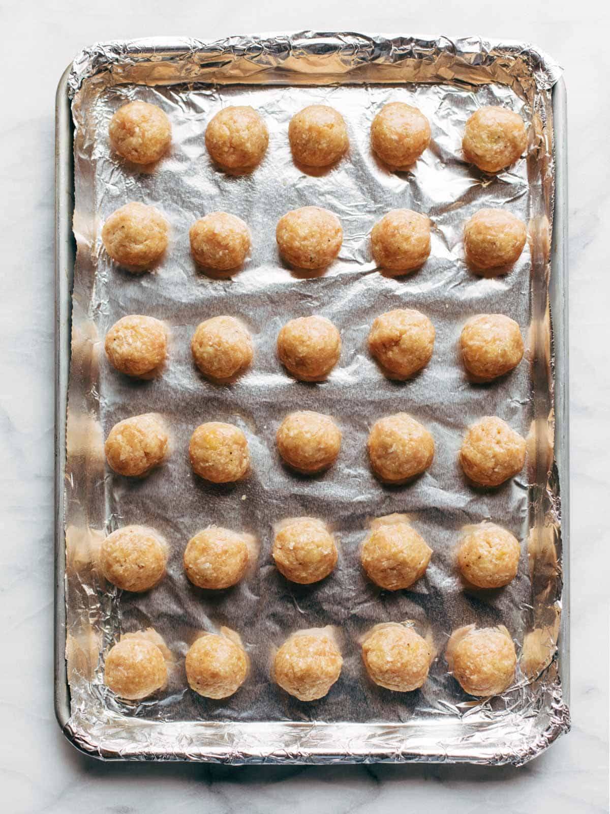 Unbaked Chicken Meatballs on a sheet pan.