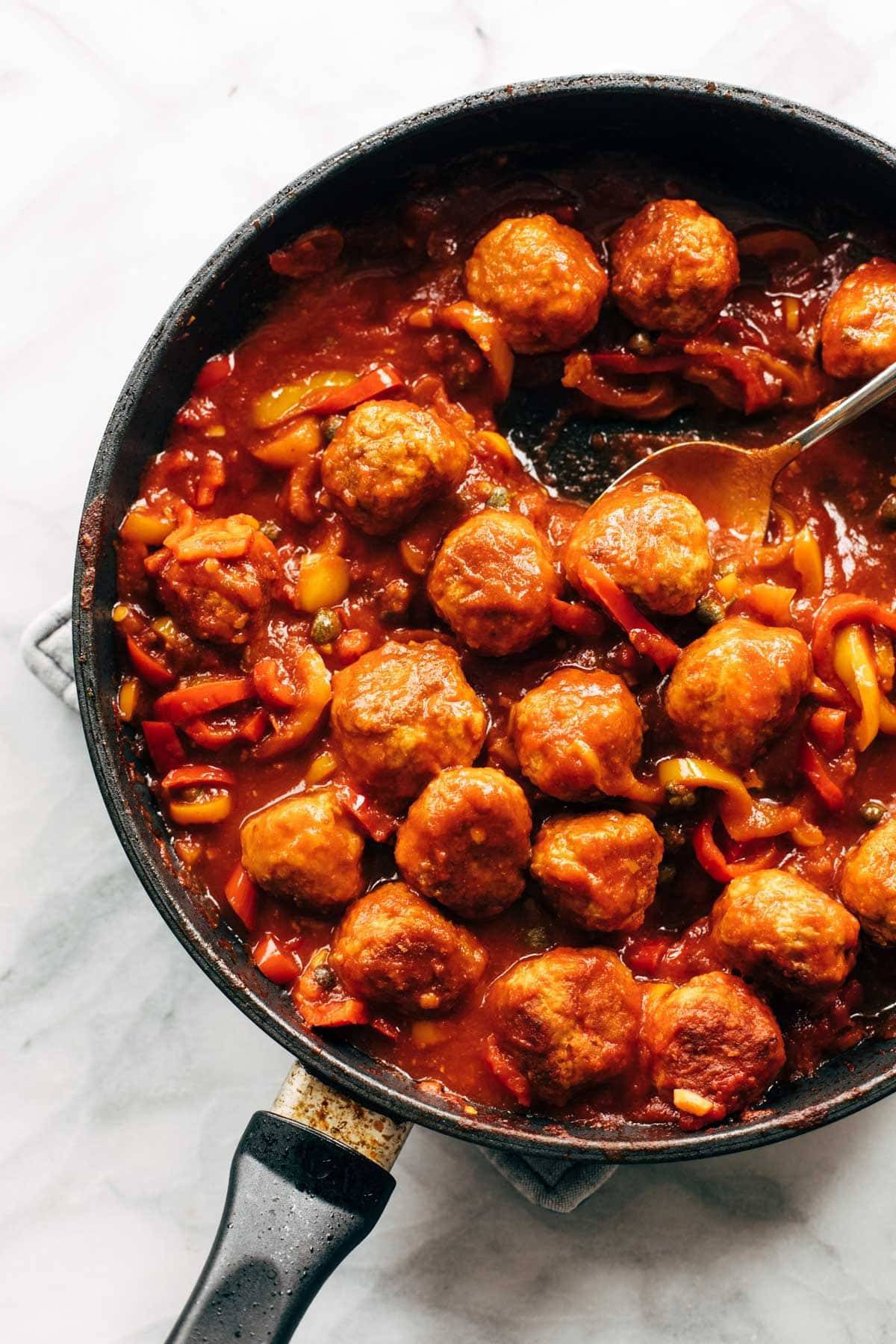 Chicken meatballs and peppers in a pan.