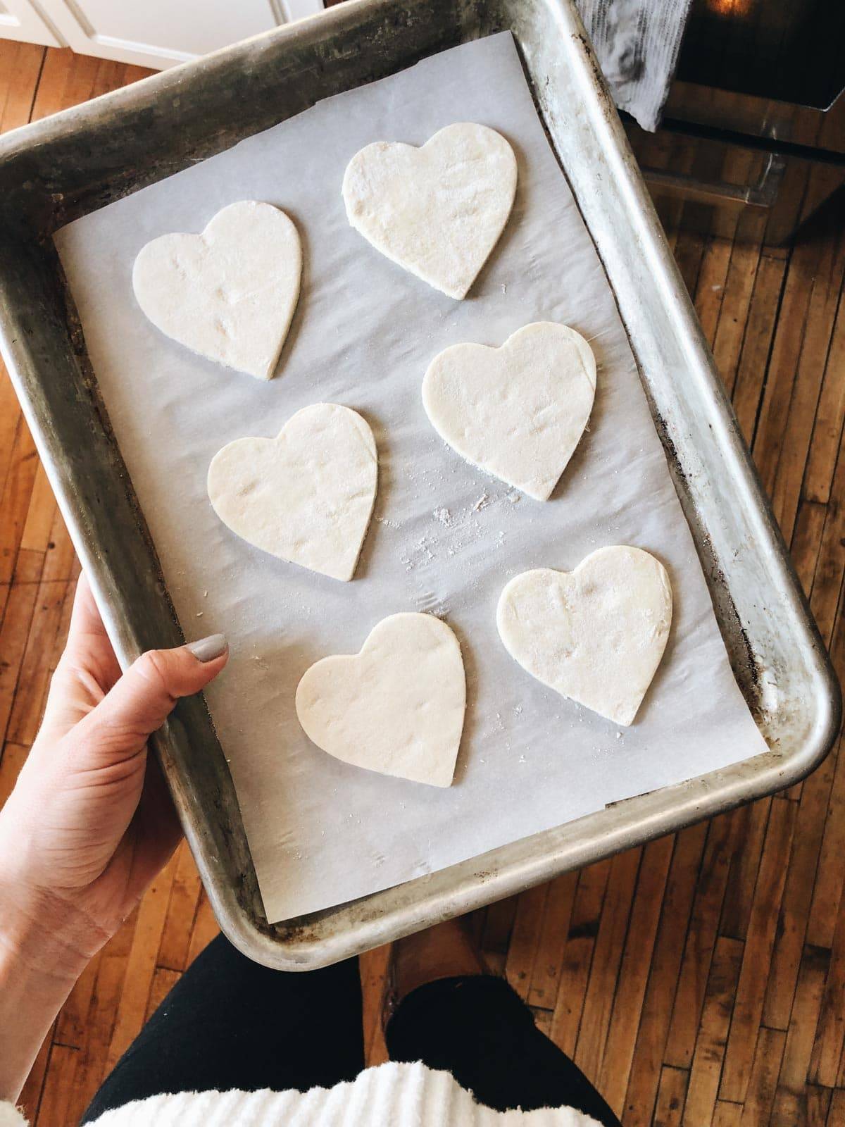 Puff pastry in heart shapes on pan before baking.