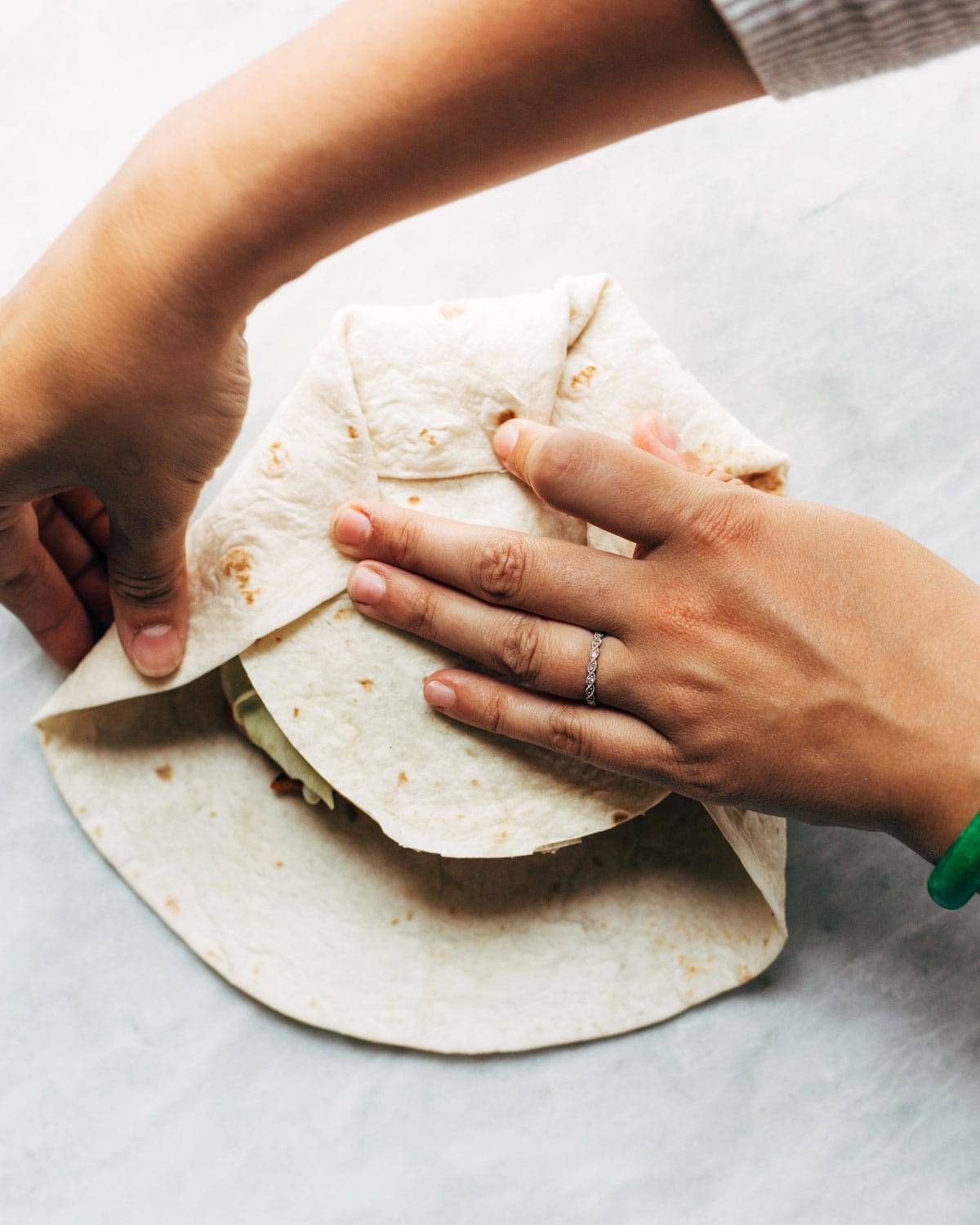 Folding up tortilla for vegan crunchwrap supreme.