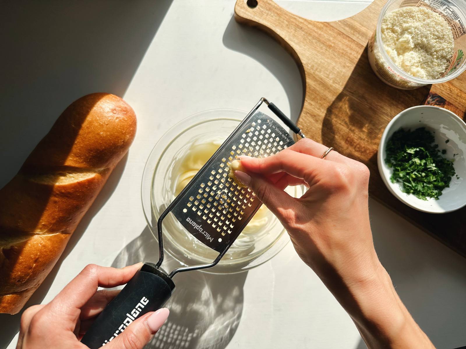 Grating garlic into bowl of butter.