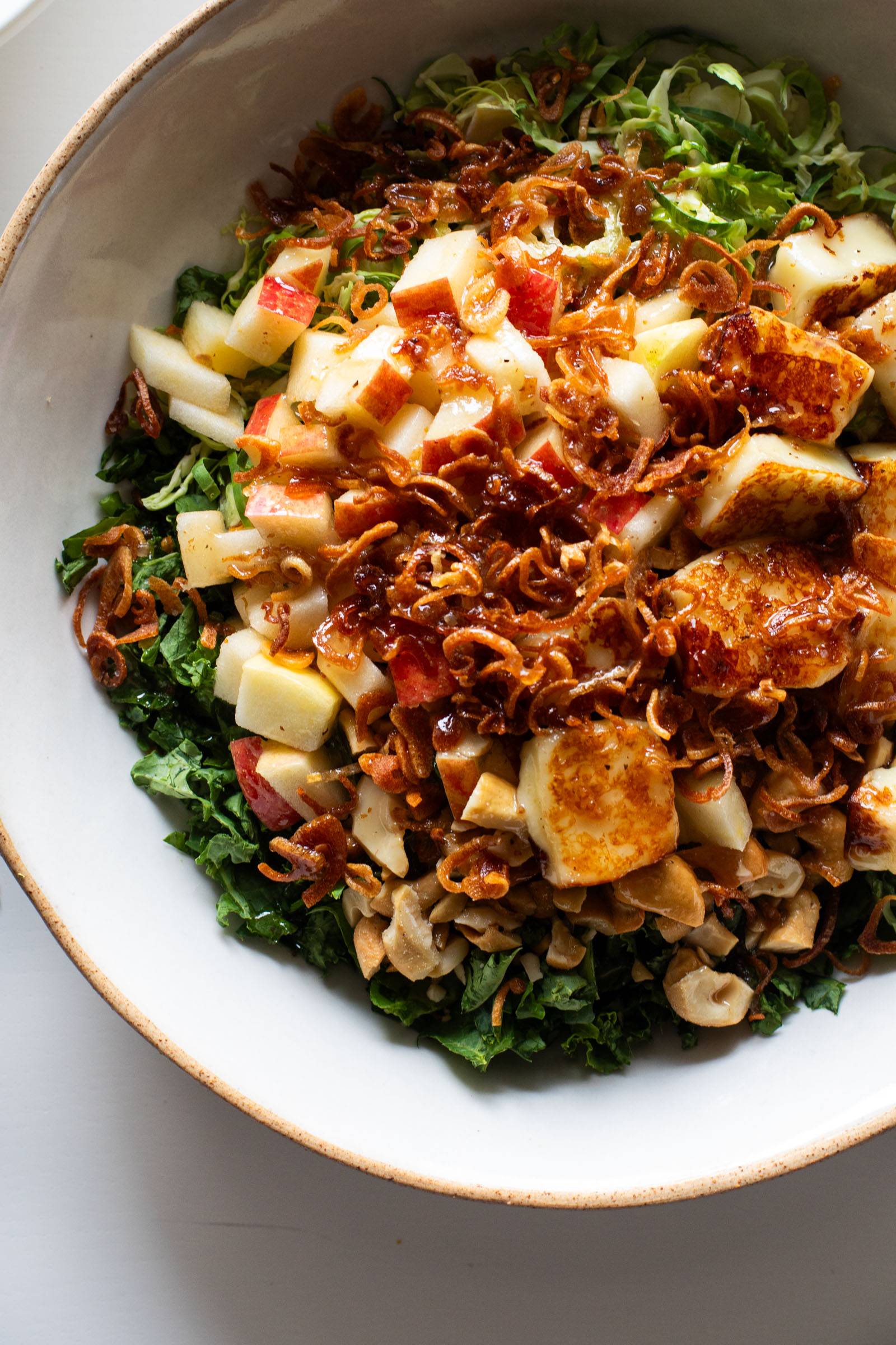 Overhead image of a big bowl of Kale Apple Salad with crispy shallots on top.