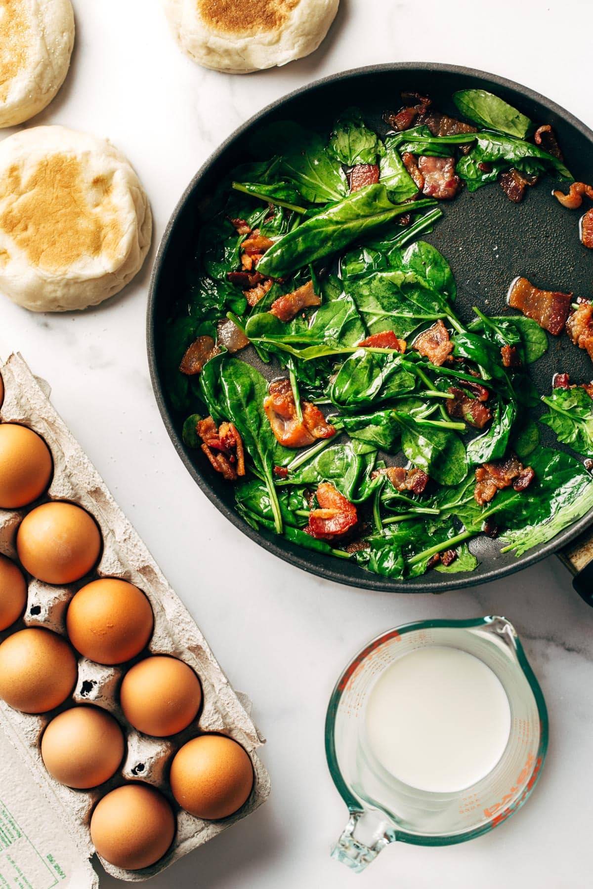 Spinach and bacon in pan with eggs.
