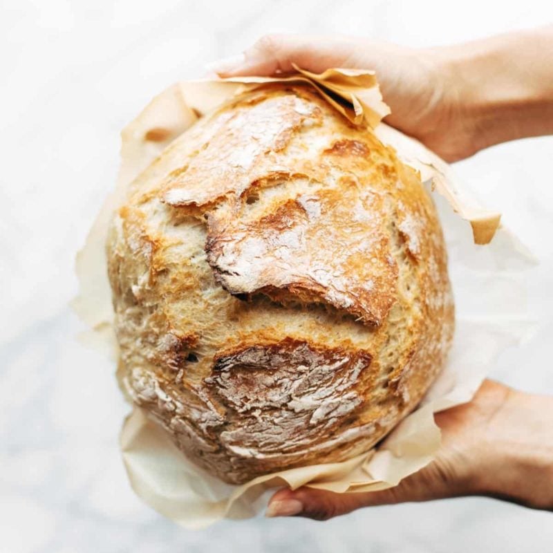White hands holding homemade no knead bread.