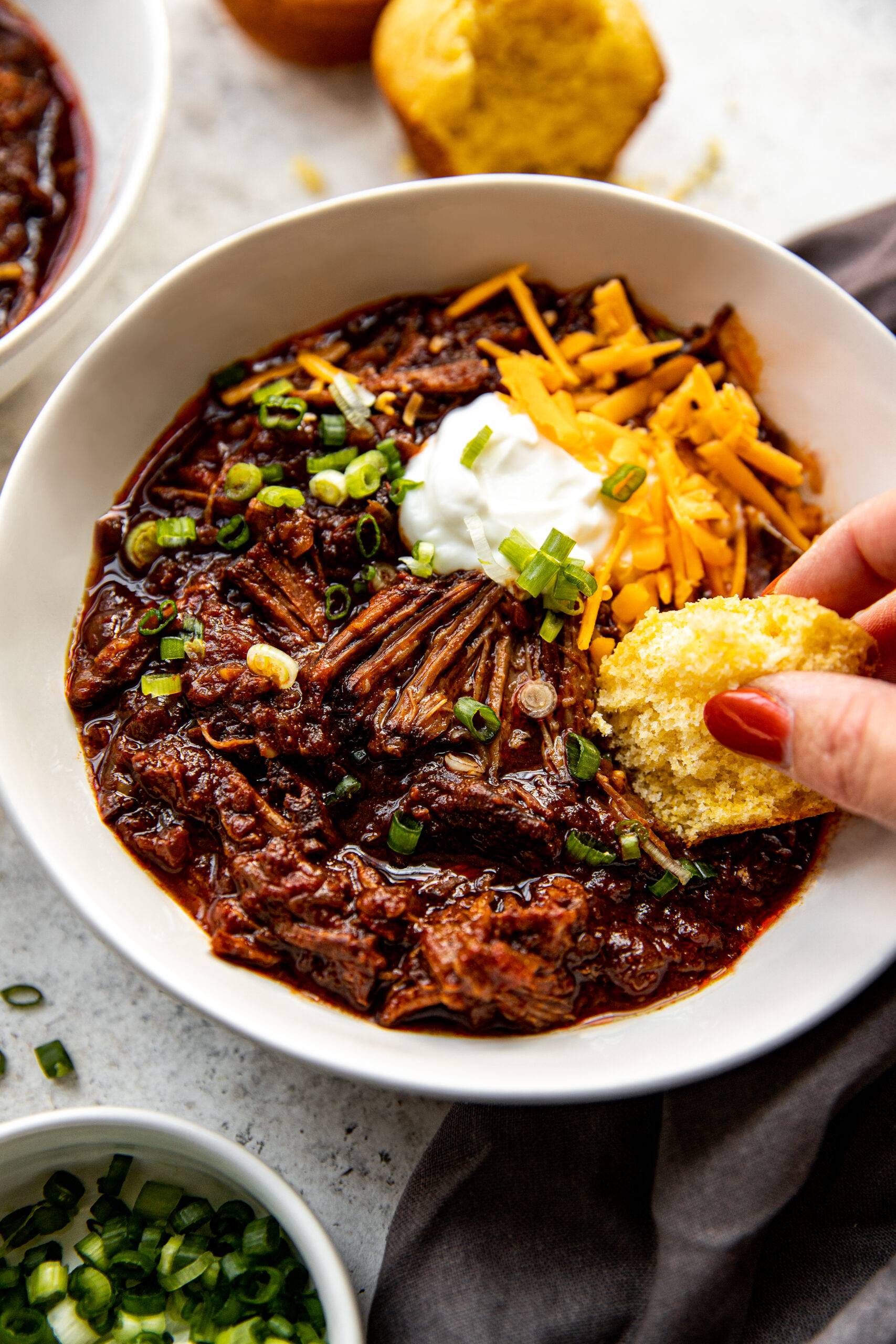 Dipping cornbread into a bowl of Texas chili with sour cream and cheese.