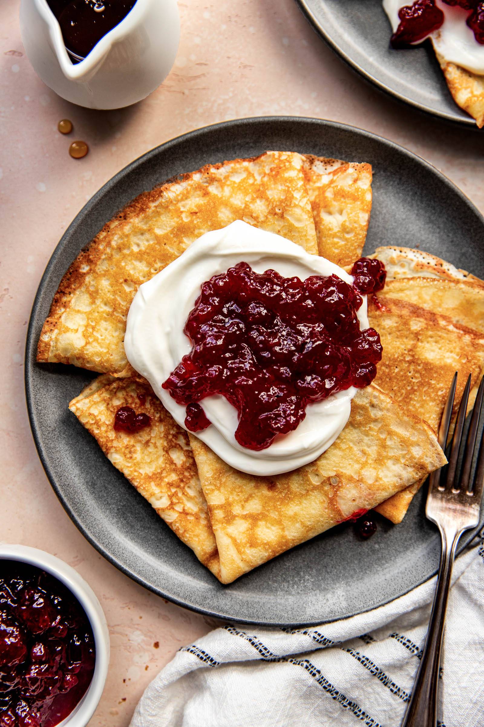 Swedish pancakes on a plate, topped with yogurt and jam.