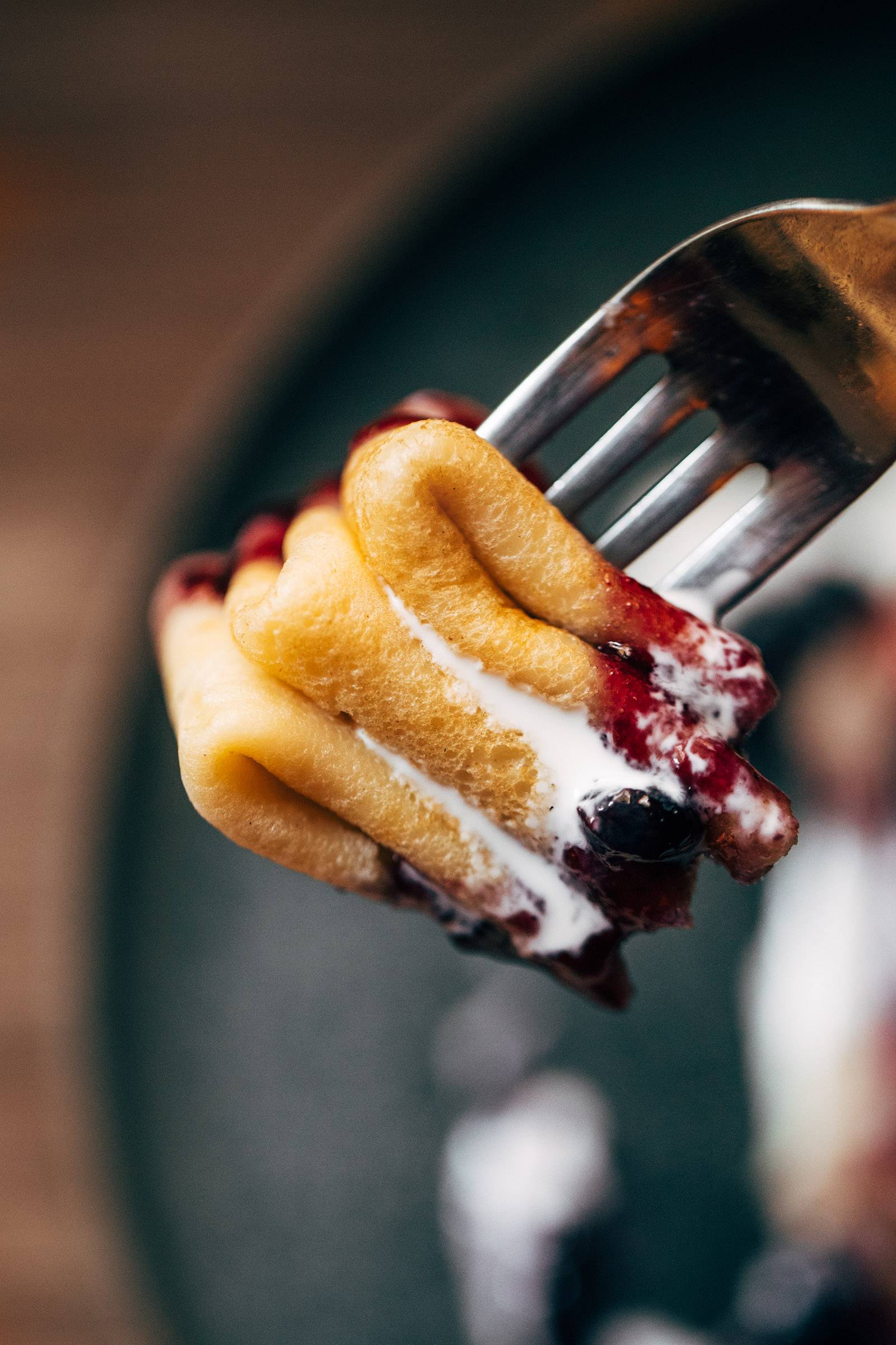 Swedish pancake bite on a fork with yogurt and jam.