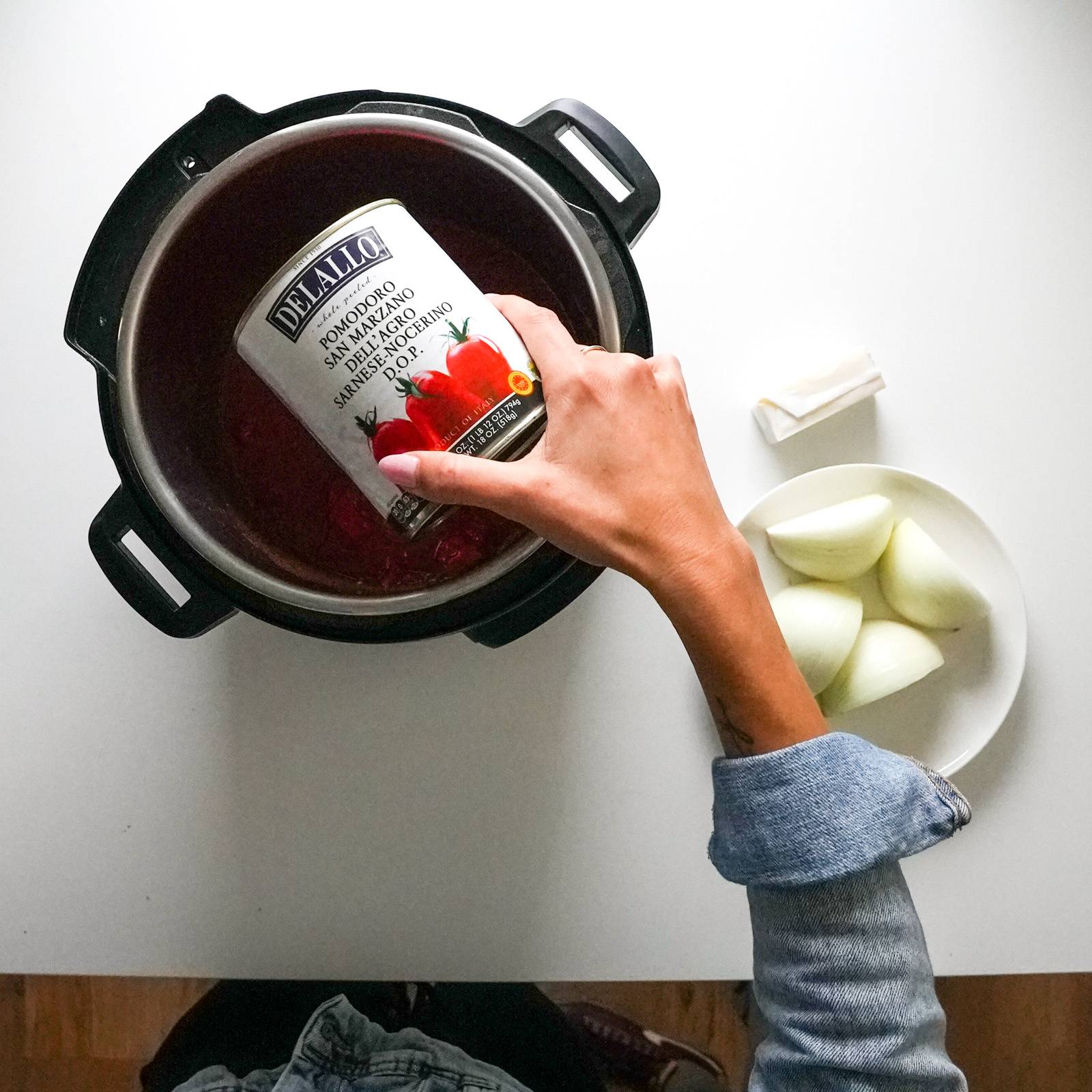 Pouring can of San Marzano Tomatoes into an Instant Pot.