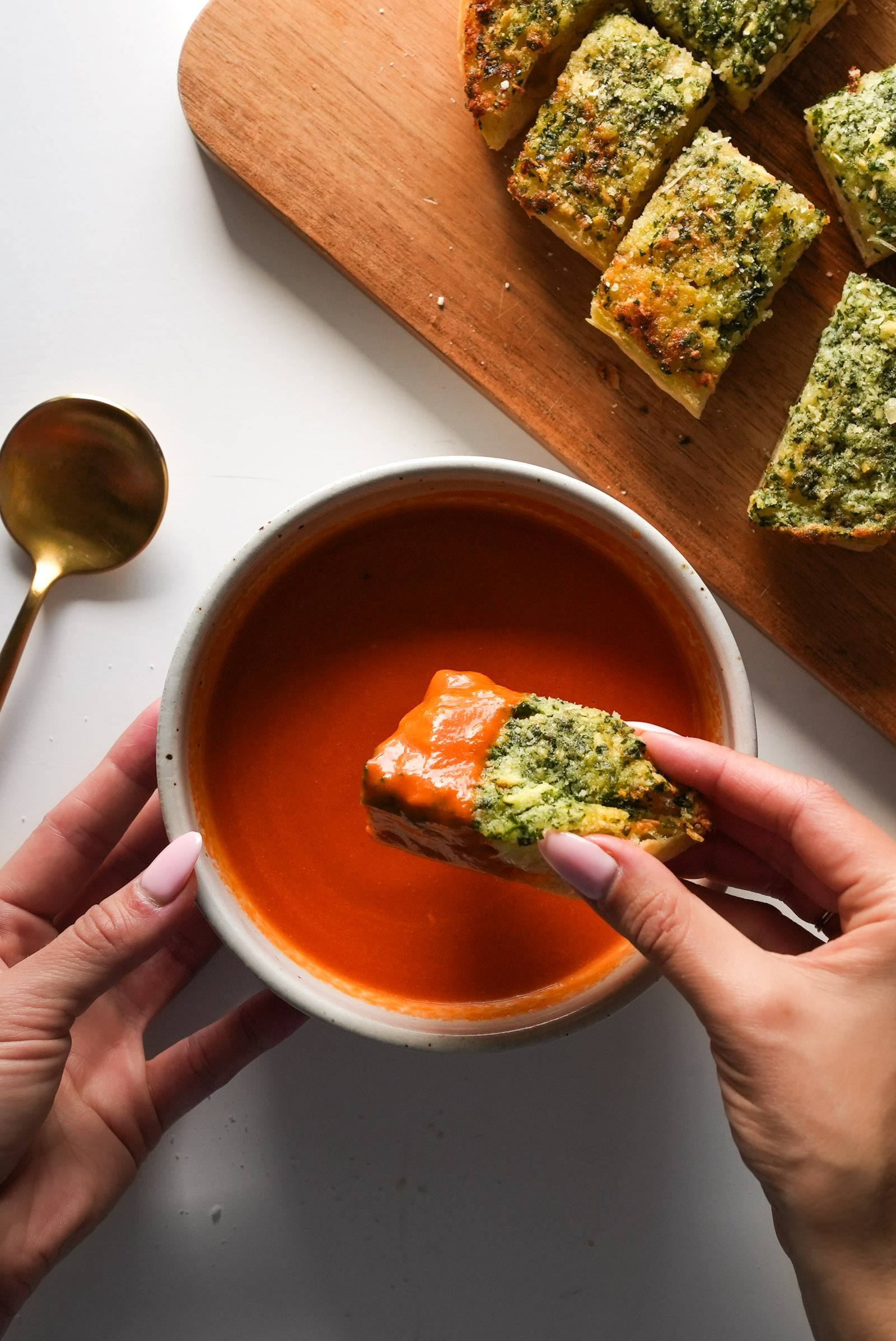 Dipping a slice of garlic bread into a bowl of tomato soup.