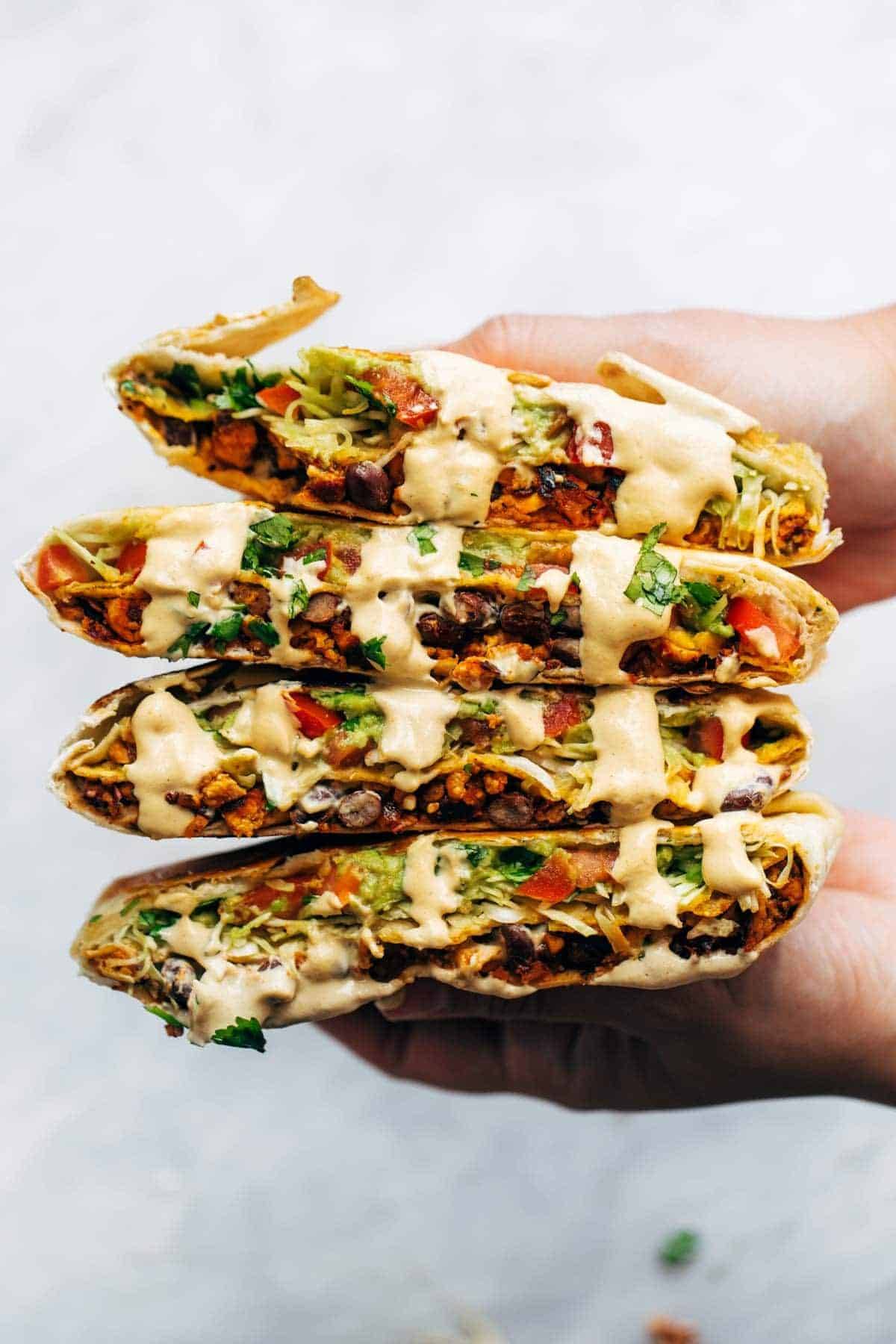 Vegan crunchwrap supreme stacked in a row.