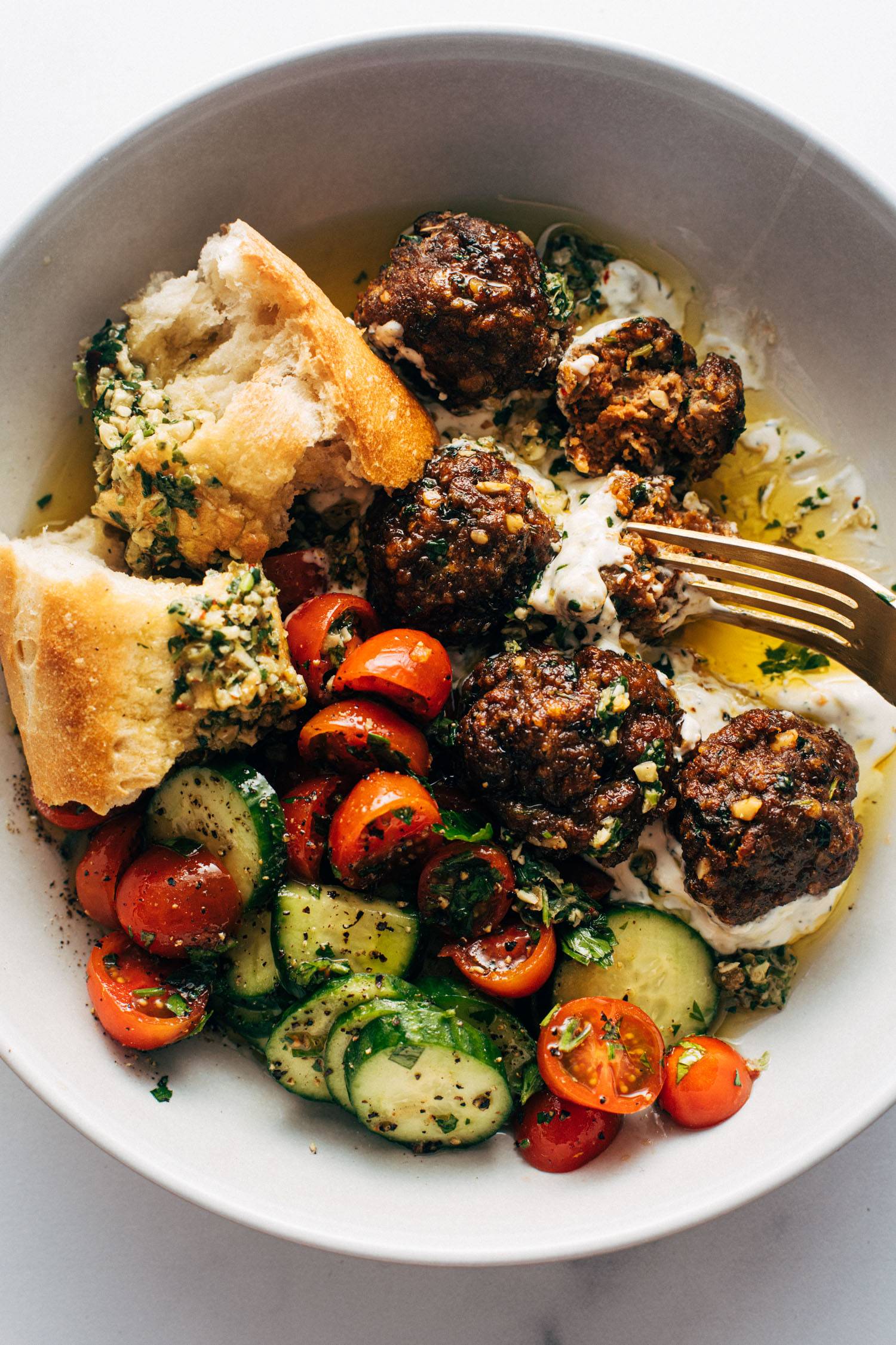 Meatballs in a bowl with a tomato salad and bread